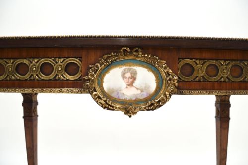 fig 1. A rectangular walnut writing table featuring a geometric inlaid border, tapering legs, gilded bronze mounts, and a central oval porcelain portrait medallion on the apron.