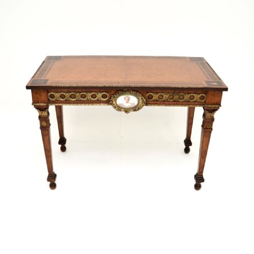 fig 2. A rectangular walnut writing table featuring a geometric inlaid border, tapering legs, gilded bronze mounts, and a central oval porcelain portrait medallion on the apron.