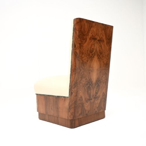 fig 1. An armless Art Deco side chair upholstered in cream leather with dark stud trim along the edges, supported by a base faced in figured burr walnut veneer.