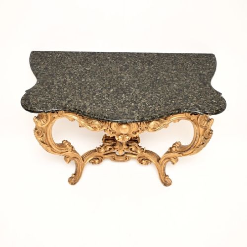 fig 1. An antique French Rococo console table featuring a carved giltwood frame with cabriole legs and a dark green marble top.