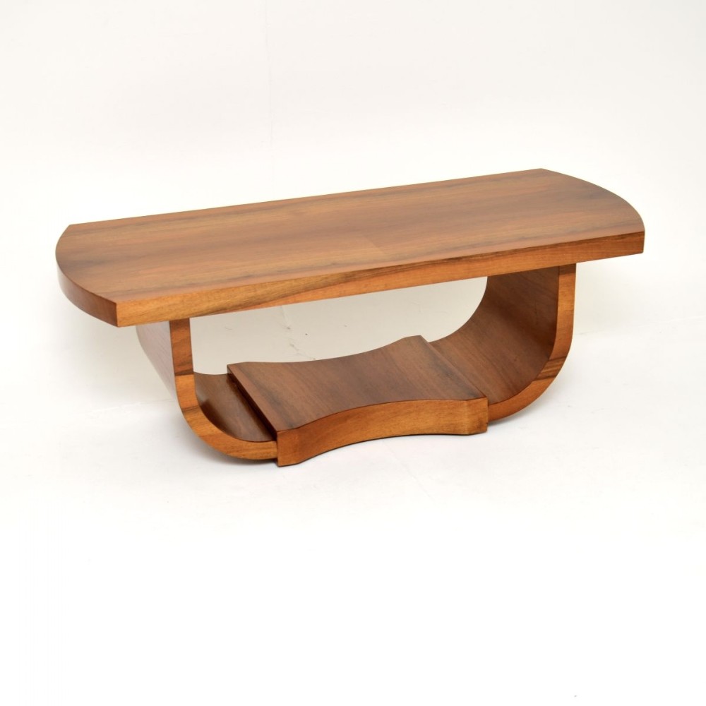 An Art Deco coffee table constructed from warm brown walnut featuring a curved U-shaped base support and a smooth rectangular top with curved ends.