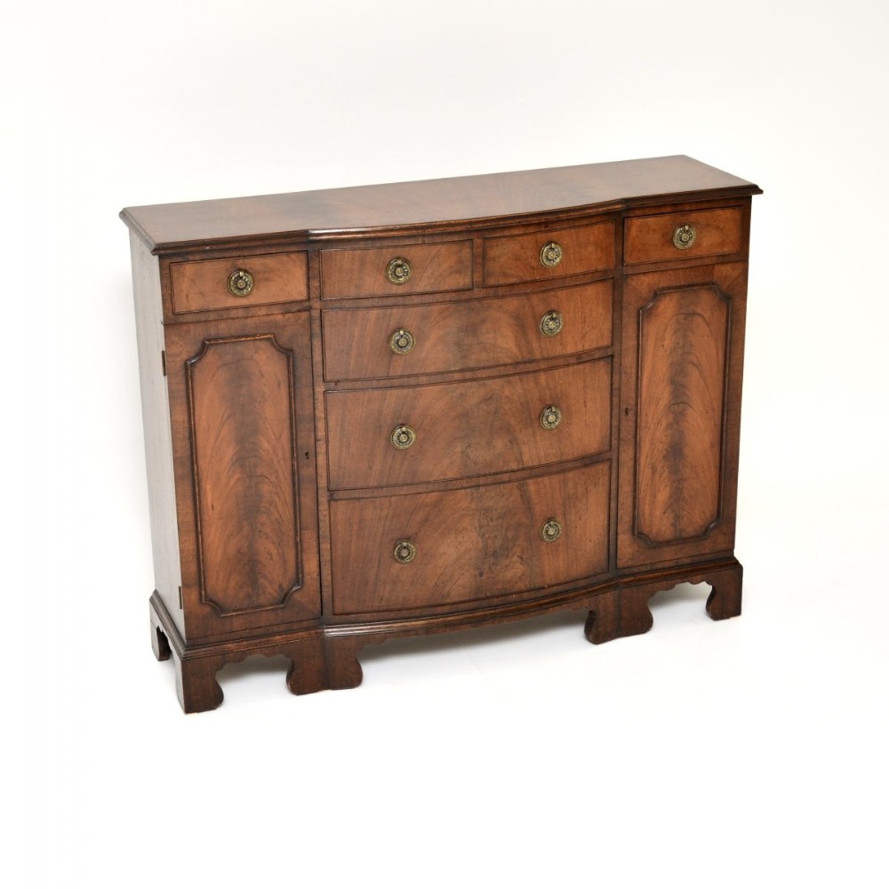 A Georgian style mahogany breakfront sideboard featuring central drawers, flanking side cupboards, brass ring handles, and shaped bracket feet.