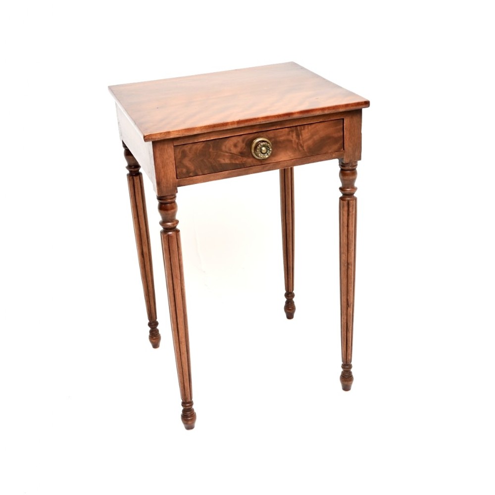 A Georgian walnut side table featuring a single drawer with a round brass handle and four slim fluted turned legs.