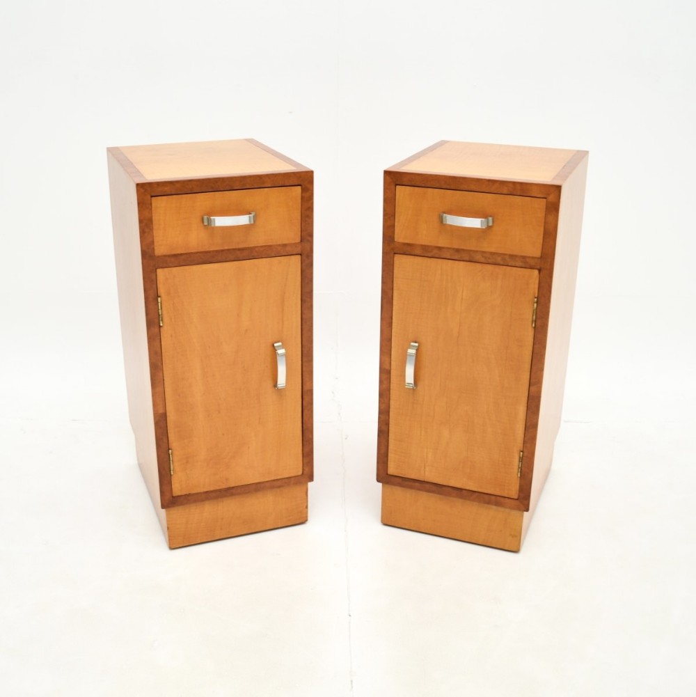 A pair of Art Deco bedside cabinets constructed from light-coloured satinwood with contrasting walnut crossbanding and silver metal handles.