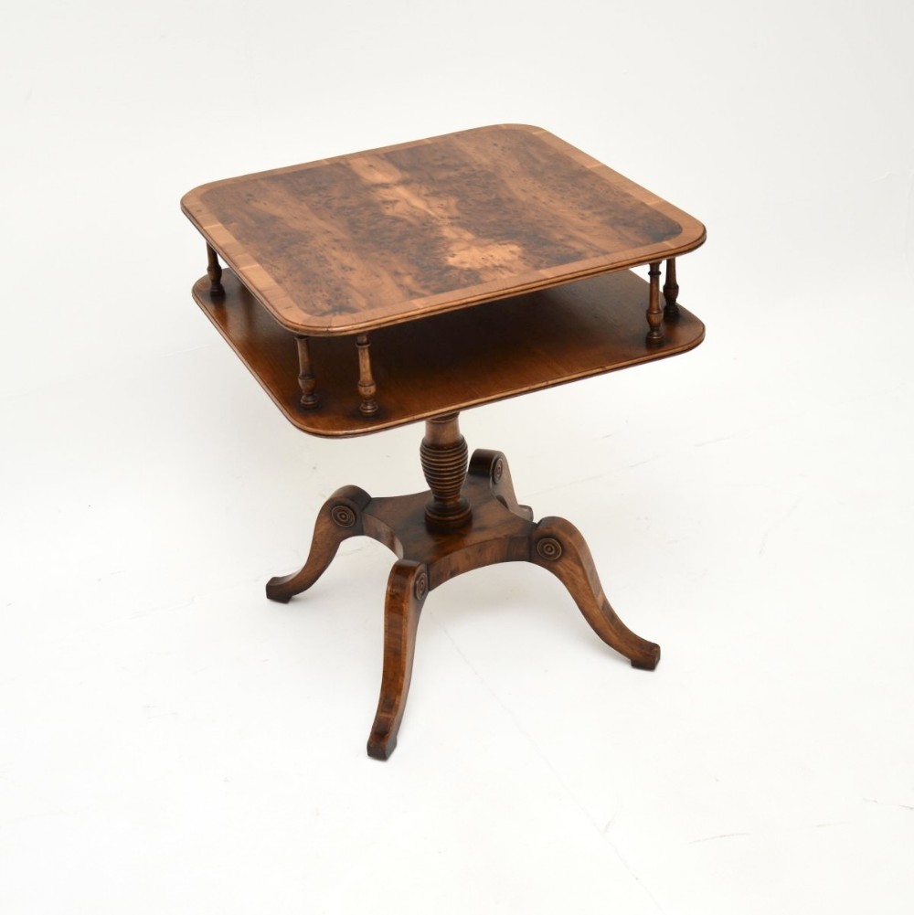 An antique yew wood side table featuring a figured square top with rounded corners, a lower shelf supported by turned spindles, and a central turned pedestal on four splayed legs.