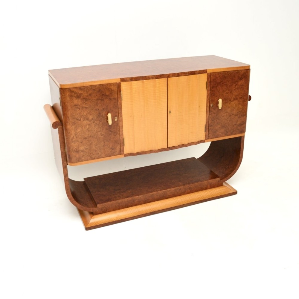 An Art Deco sideboard crafted from burr walnut with contrasting blonde sycamore central doors, set on a curved pedestal base.