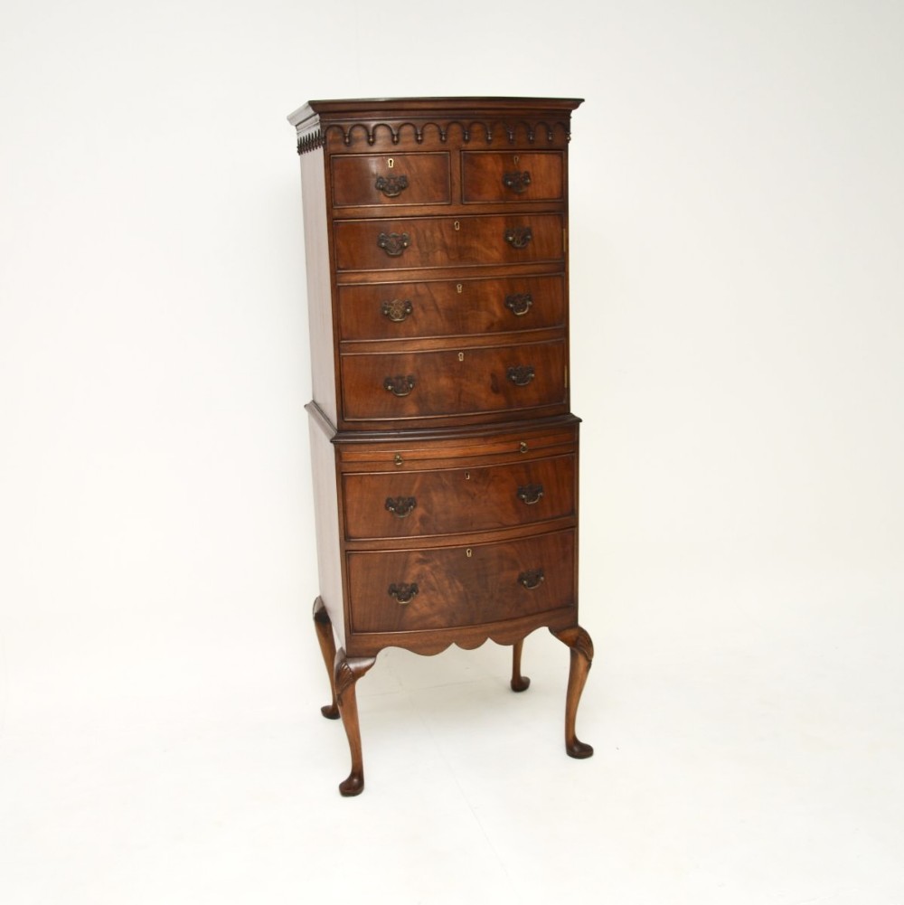 A tall mahogany chest on legs featuring a two-section drawer cabinet, carved top cornice moulding, brass drop handles, and carved cabriole legs.