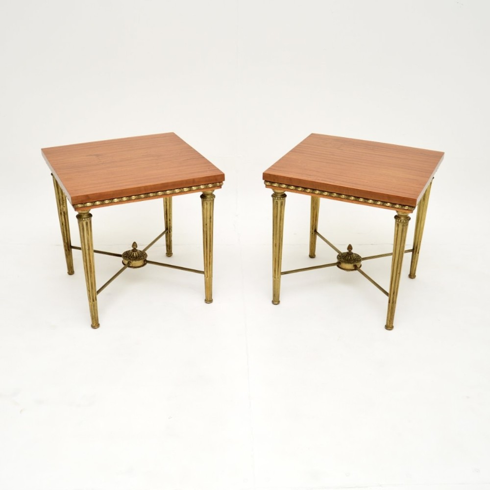 A pair of square satinwood side tables featuring beaded brass aprons, fluted brass legs, and X-frame stretchers with central finials.