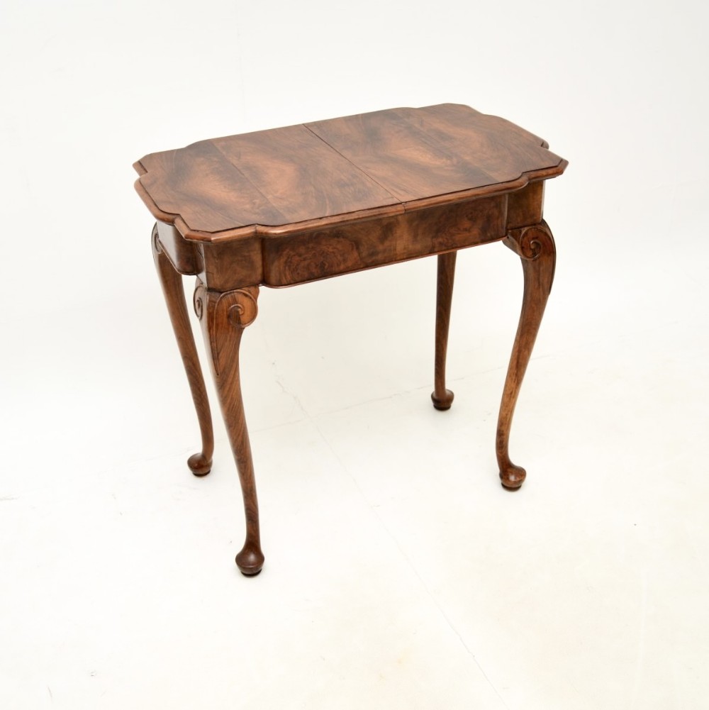 A figured walnut occasional side table featuring a shaped top with veneer grain, a deep apron, and slender cabriole legs ending in pad feet.