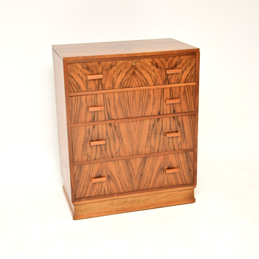 An Art Deco chest of drawers crafted in warm brown figured walnut, featuring four drawers with geometric wood handles and a stepped plinth base.