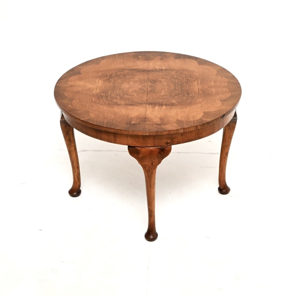A low circular burr walnut coffee table featuring a decorative scalloped veneered top and slender cabriole legs.