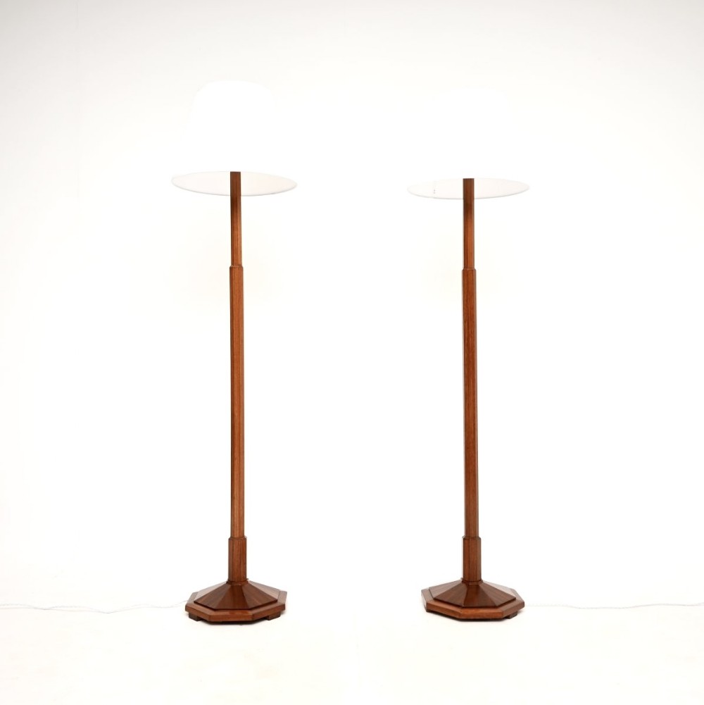 A pair of Art Deco walnut floor lamps featuring octagonal stepped bases, slender faceted stems, integrated glass trays, and white shades.