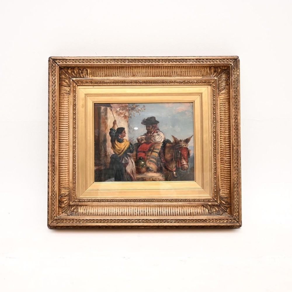 A nineteenth-century framed oil painting depicting figures in traditional dress alongside a donkey, housed in an ornate carved gold giltwood frame.