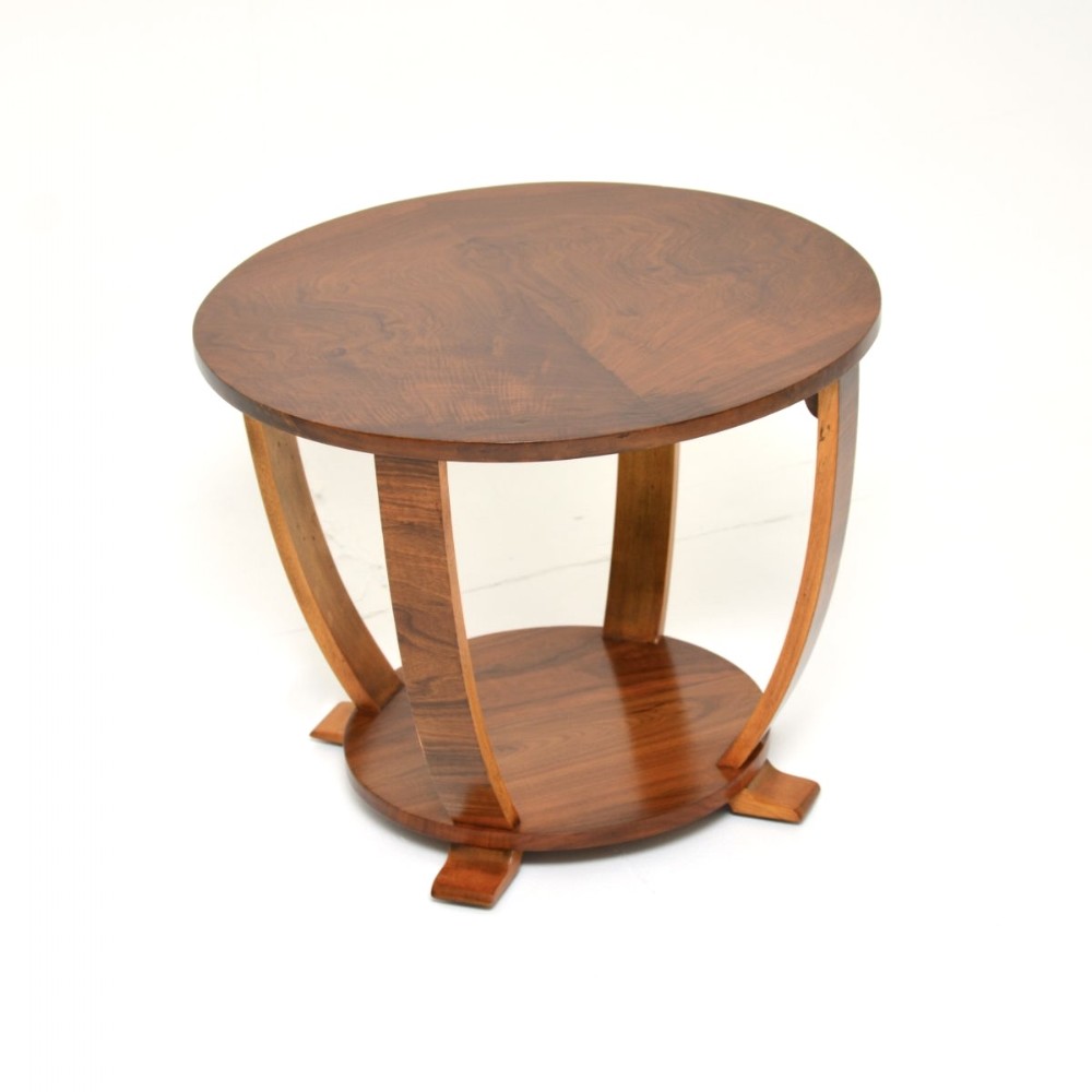 An Art Deco circular side table made of figured walnut with four sweeping curved legs and a round lower shelf tier resting on block feet.
