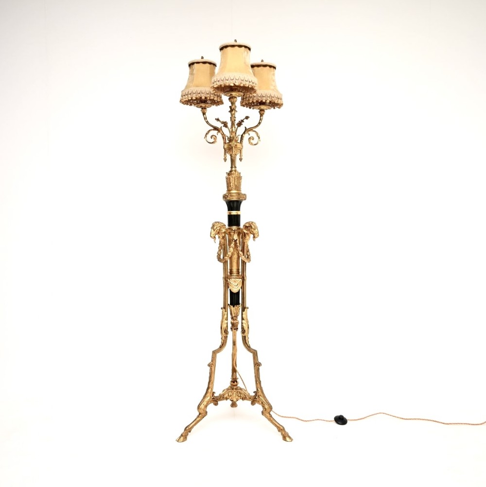 A French gilt bronze three-light floor lamp with fabric shades, ram head embellishments, and a tripod base.