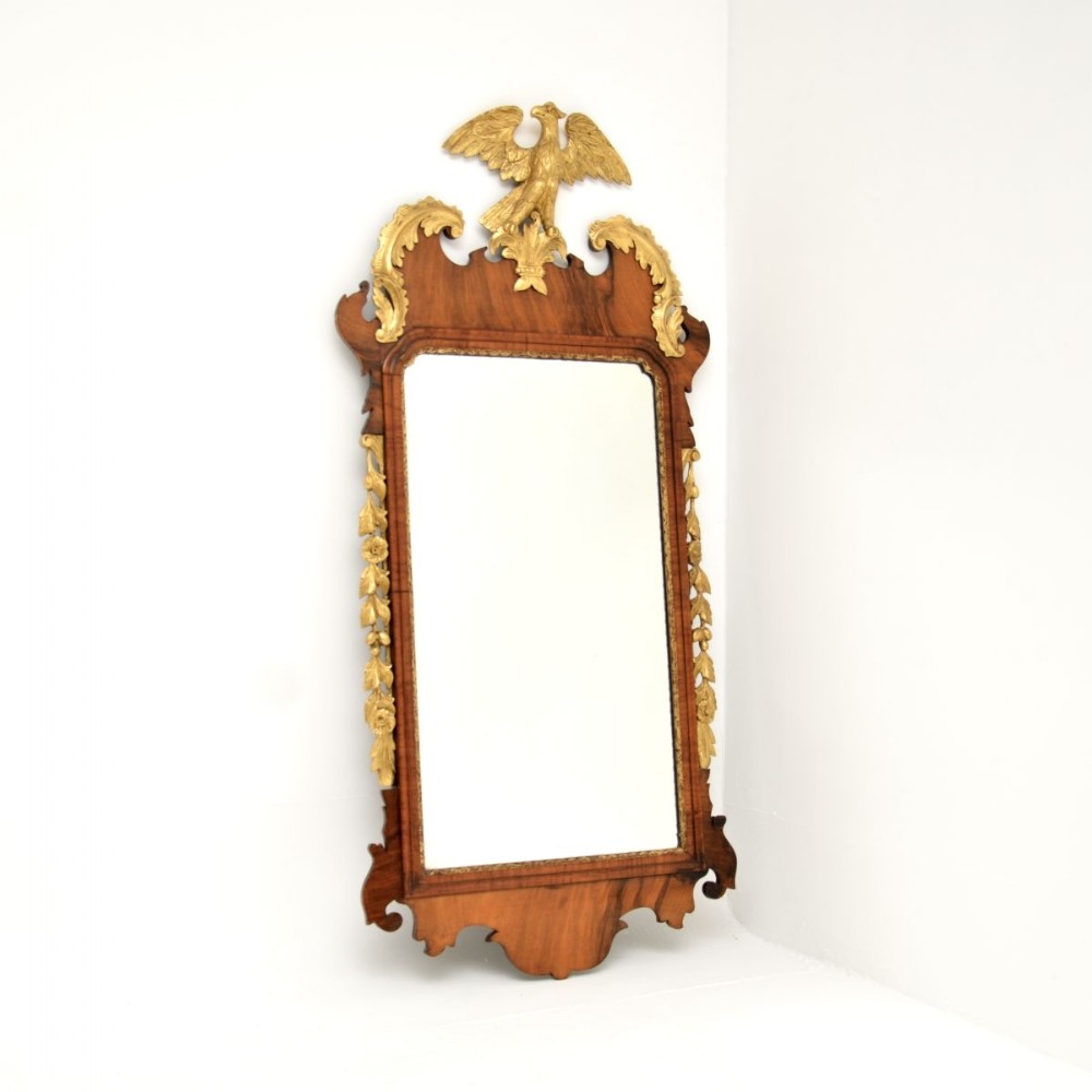 A Georgian period mahogany parcel gilt wall mirror featuring a carved golden eagle crest and side foliage garlands.