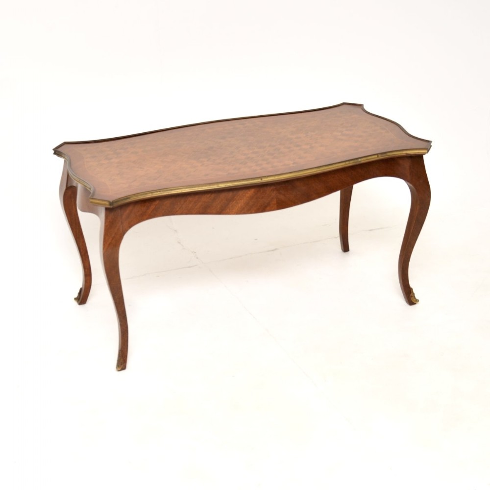 A low French Louis XV style coffee table with a geometric parquetry wood top, brass rim, curved apron, and cabriole legs.