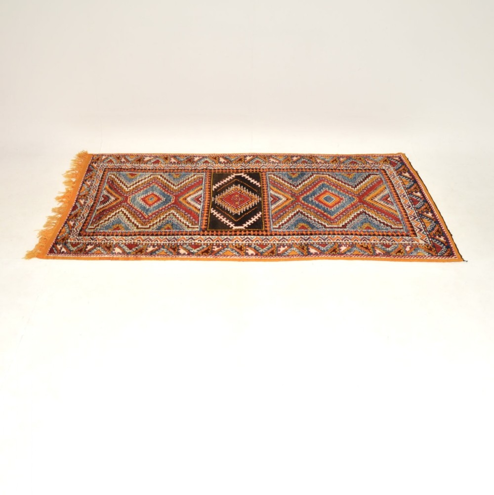 A hand-knotted antique Persian wool rug runner with geometric diamond motifs in red, blue, and yellow shades.