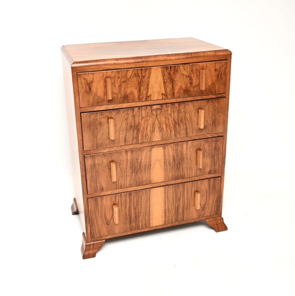 An Art Deco four-drawer chest made of figured walnut veneer with vertical wood handles and shaped bracket feet.