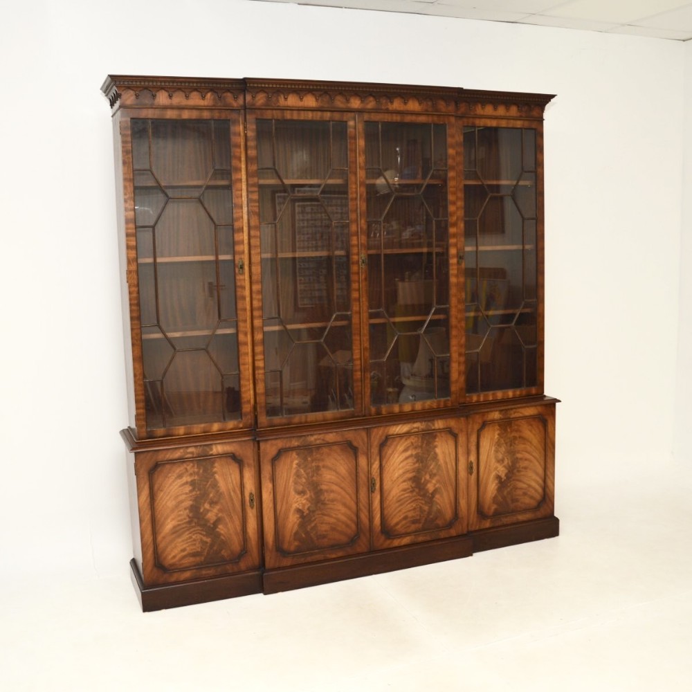 A large Georgian style mahogany breakfront bookcase featuring upper glazed doors with geometric astragal glazing and flame mahogany panelled doors on the lower section.