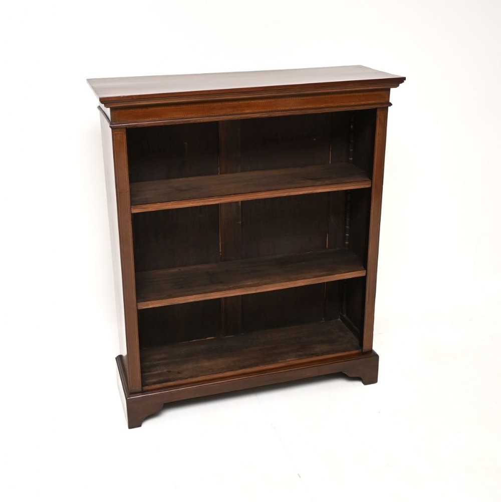 An Edwardian open mahogany bookcase featuring inlaid stringing details, three open shelving tiers, and bracket feet.