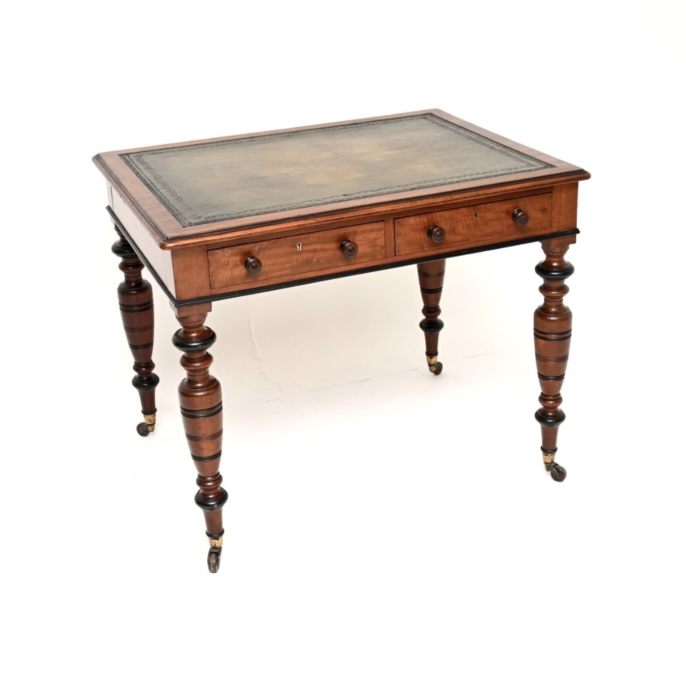 A Victorian mahogany writing desk featuring a leather inset top, two frieze drawers with wooden knob handles, and turned legs ending in brass castors.