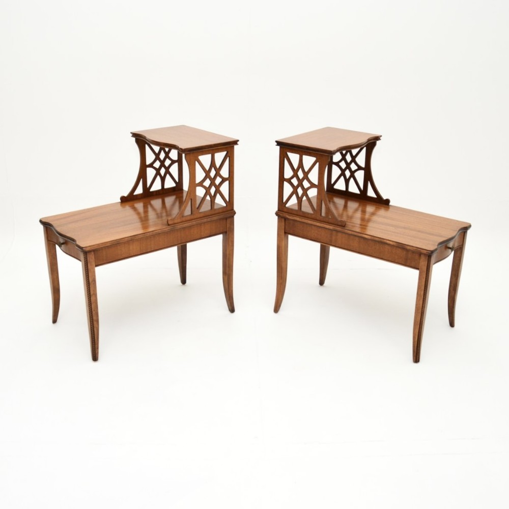 A pair of warm brown mahogany two-tier side tables featuring carved lattice fretwork supports and tapered legs.