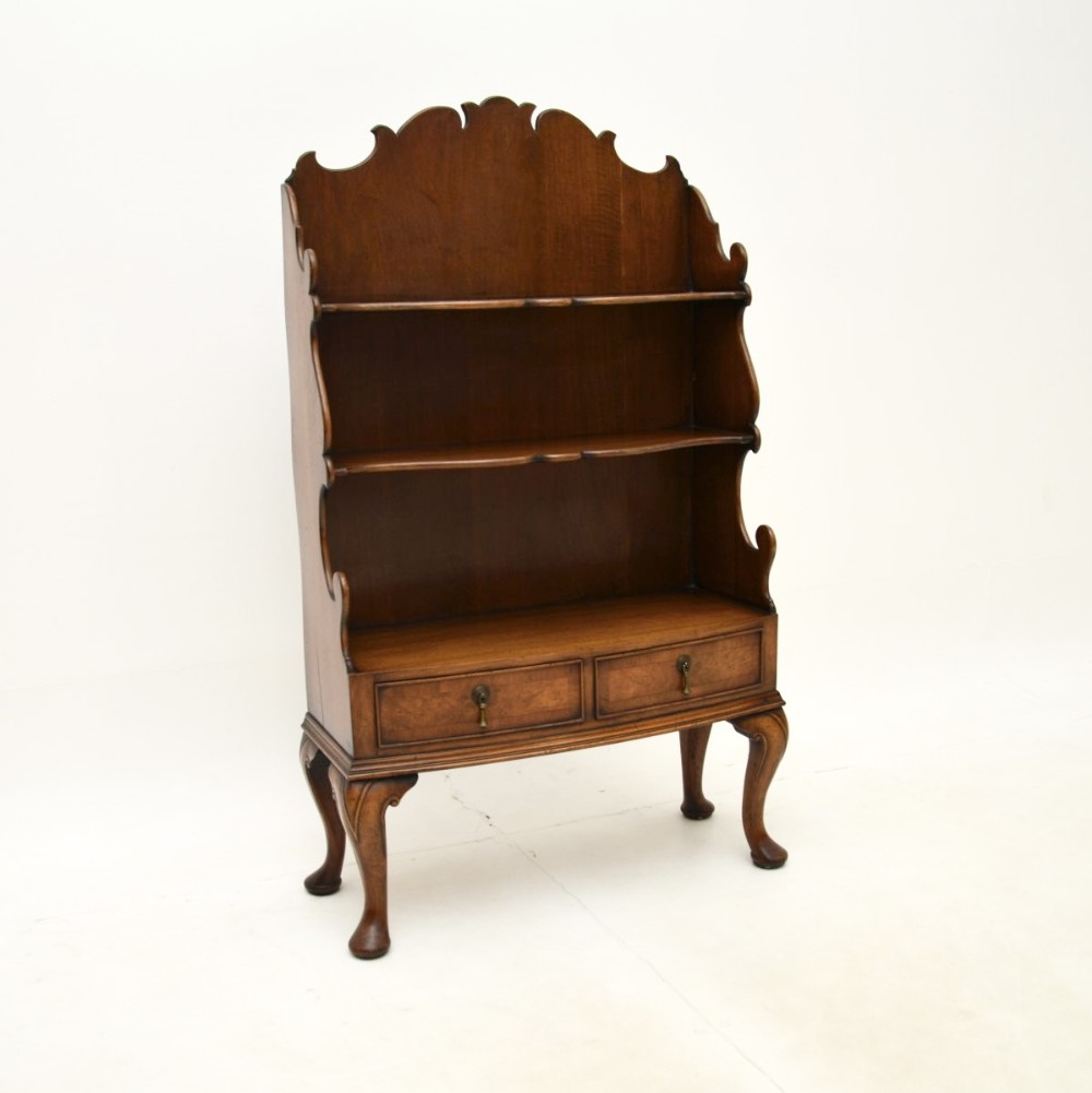 An antique burr walnut open bookcase with three cascading shelves, two lower drawers with drop handles, and cabriole legs.