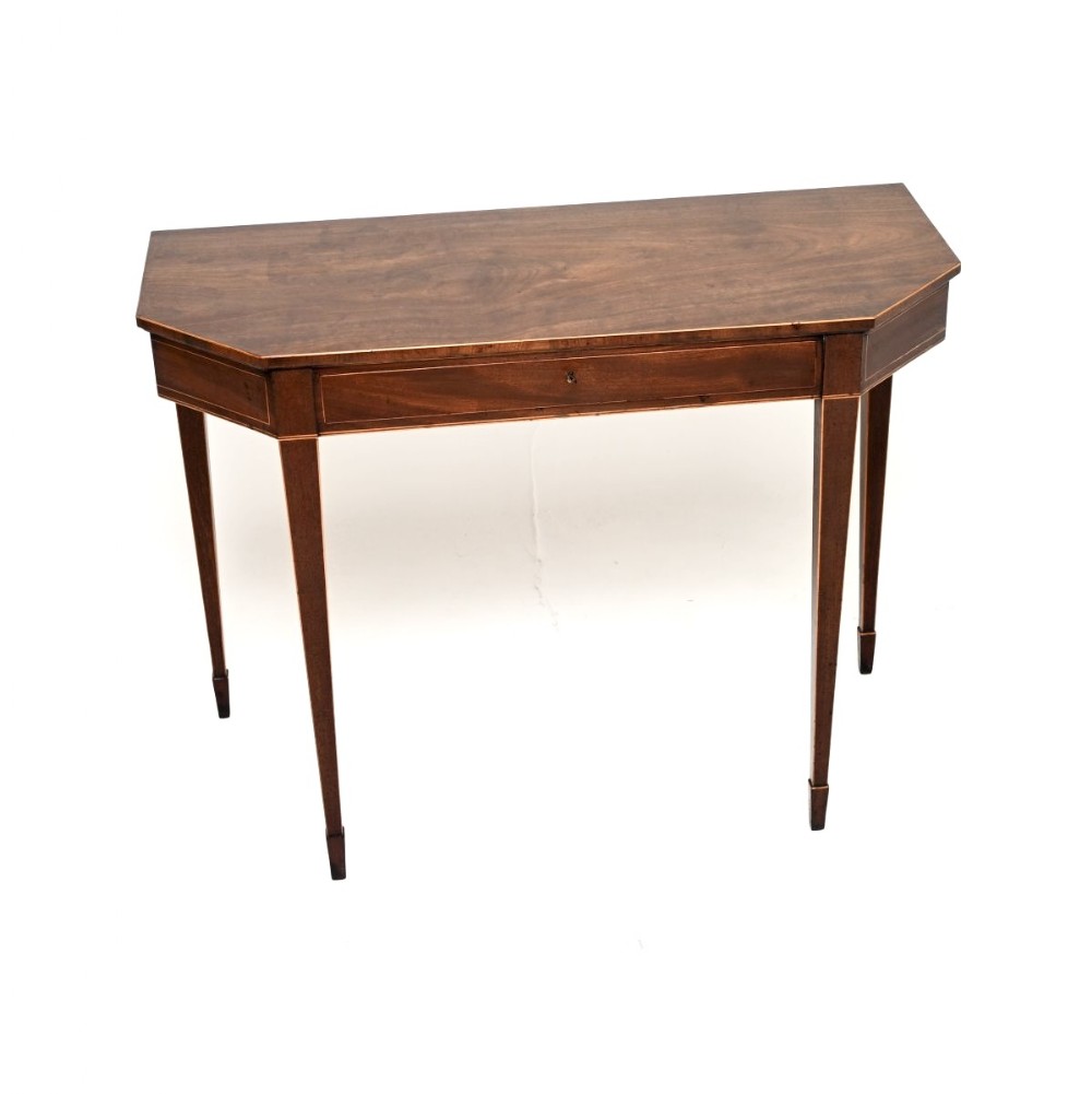 A Georgian mahogany console table featuring canted corners, boxwood stringing, and tapered square legs.