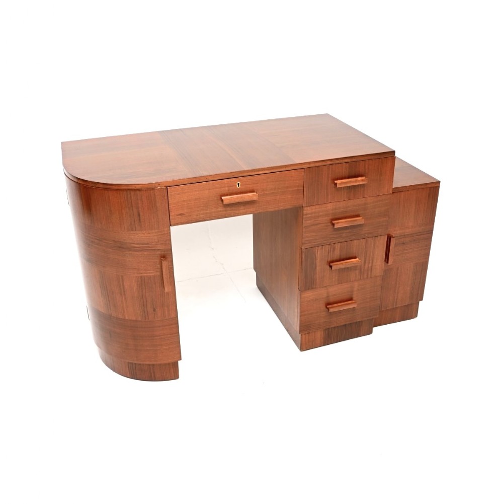 An Art Deco figured walnut desk featuring a curved pedestal cabinet, a stack of drawers with rectangular wooden handles, and a central kneehole drawer.