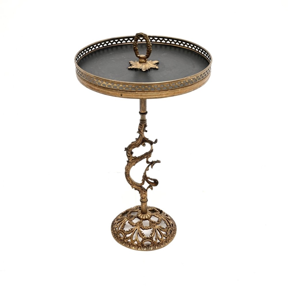 An antique French brass side table featuring a circular black leather top, a pierced gallery rim, a central ring handle, an ornate scrolling brass stem, and a pierced circular base.