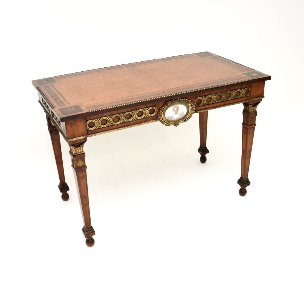 A rectangular walnut writing table featuring a geometric inlaid border, tapering legs, gilded bronze mounts, and a central oval porcelain portrait medallion on the apron.