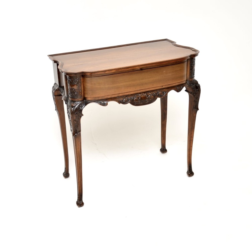 An antique Victorian carved walnut console table featuring a serpentine front, detailed apron carvings, and slender cabriole legs.