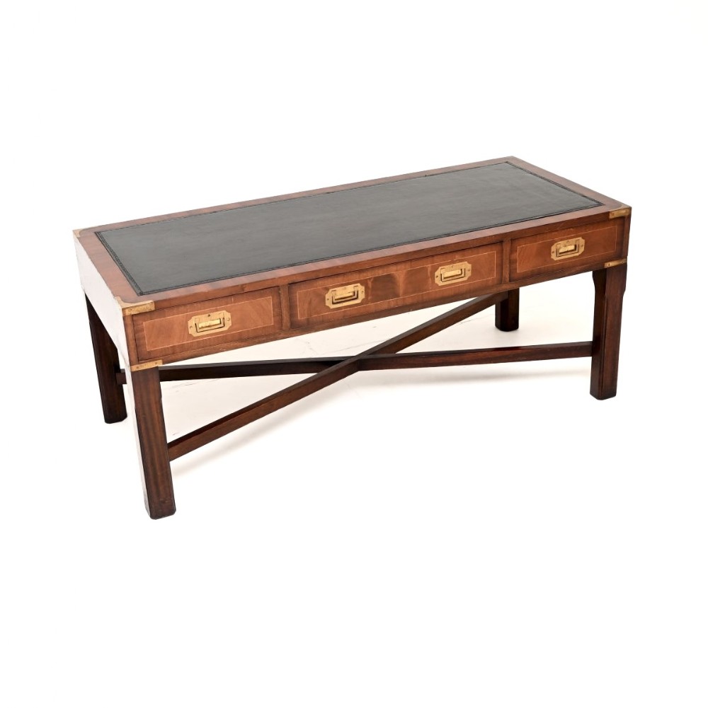 A rectangular dark mahogany military campaign style coffee table with an inset black leather top, three drawers with flush brass handles, and an X-frame cross stretcher base.