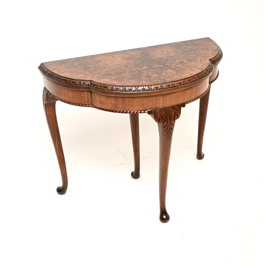 A Queen Anne style burr walnut fold-over card table featuring cabriole legs with carved knee accents and pad feet.