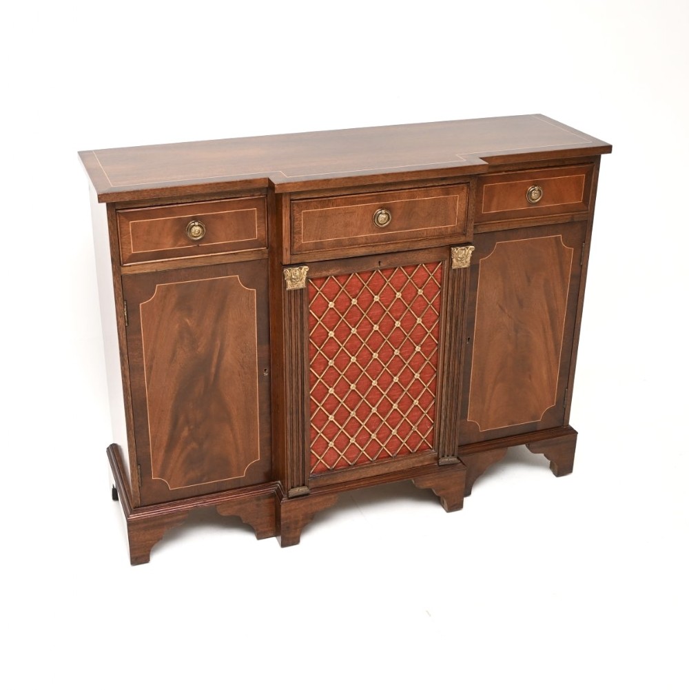 A Georgian style mahogany sideboard with boxwood stringing, featuring a central drawer above a brass lattice grille door backed with red fabric, flanked by drawers and cupboard doors.