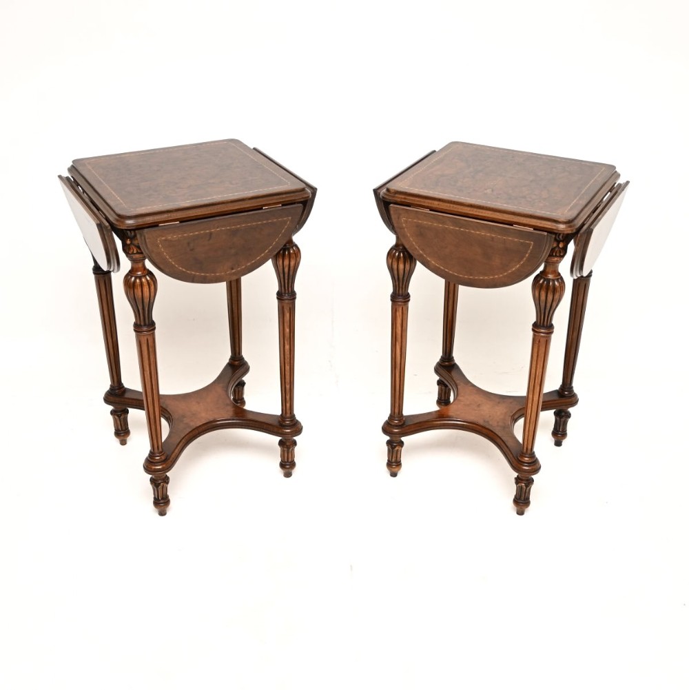 A matching pair of warm brown walnut side tables with drop-leaf tops, linear inlay details, fluted legs, and shaped stretchers.