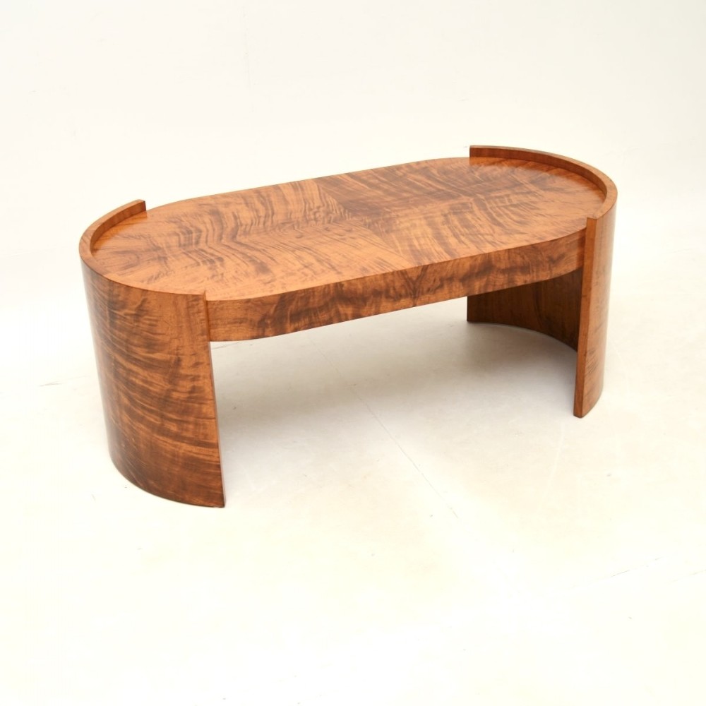 A low oval Art Deco coffee table crafted from figured burr walnut veneer with curved end panels.