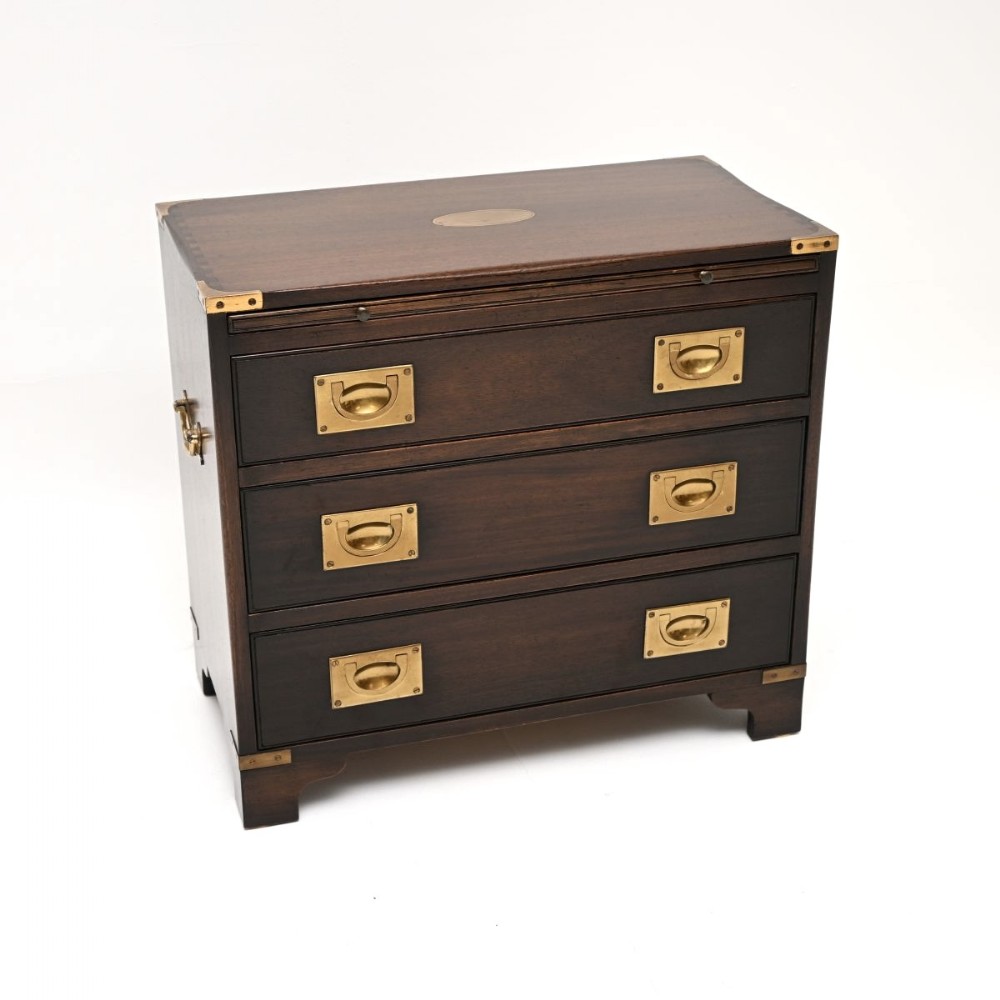 A dark mahogany three-drawer military campaign chest featuring flush brass corner mounts and brass drop handles.