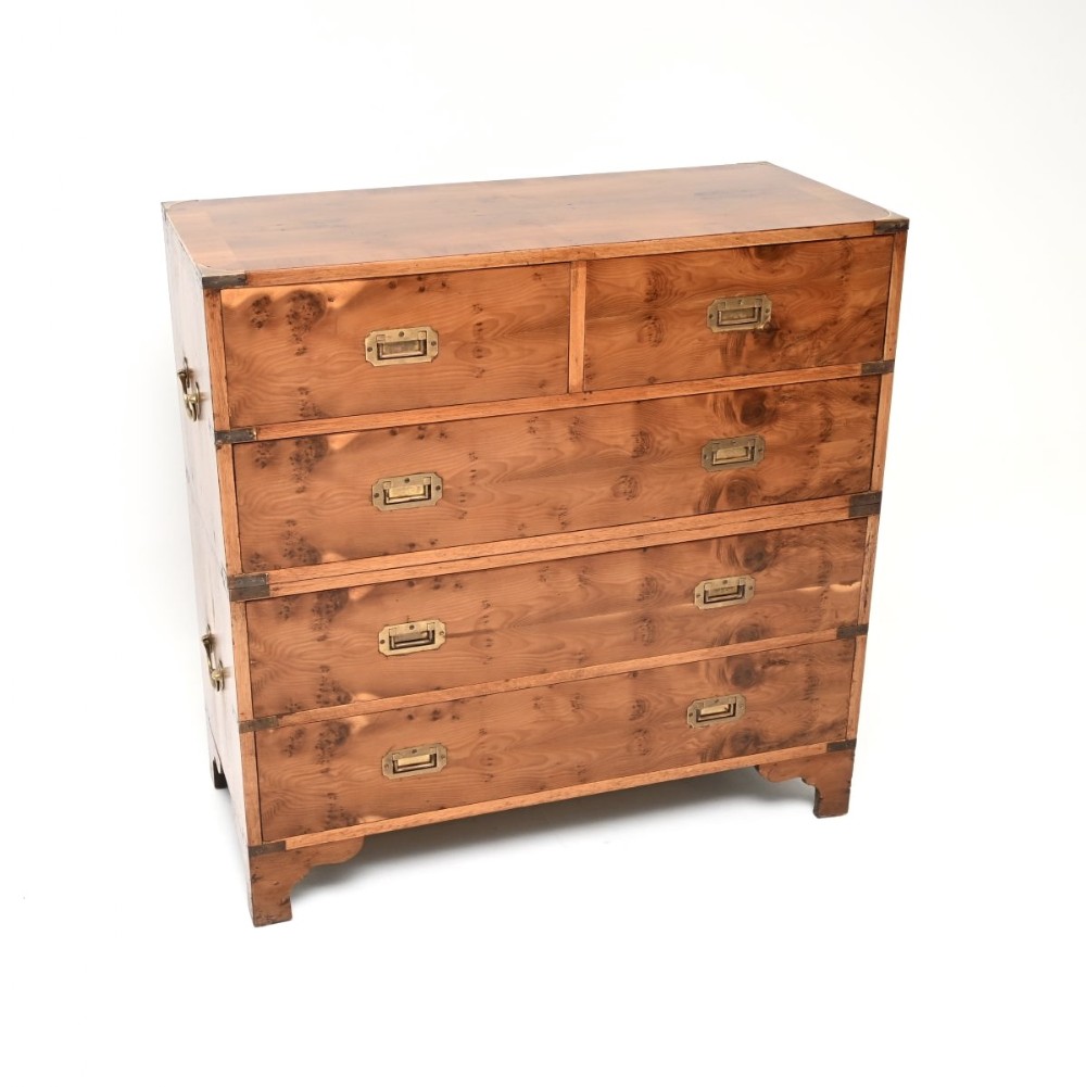 An antique yew wood military campaign chest of drawers featuring two modular sections with flush brass handles and protective corner fittings.