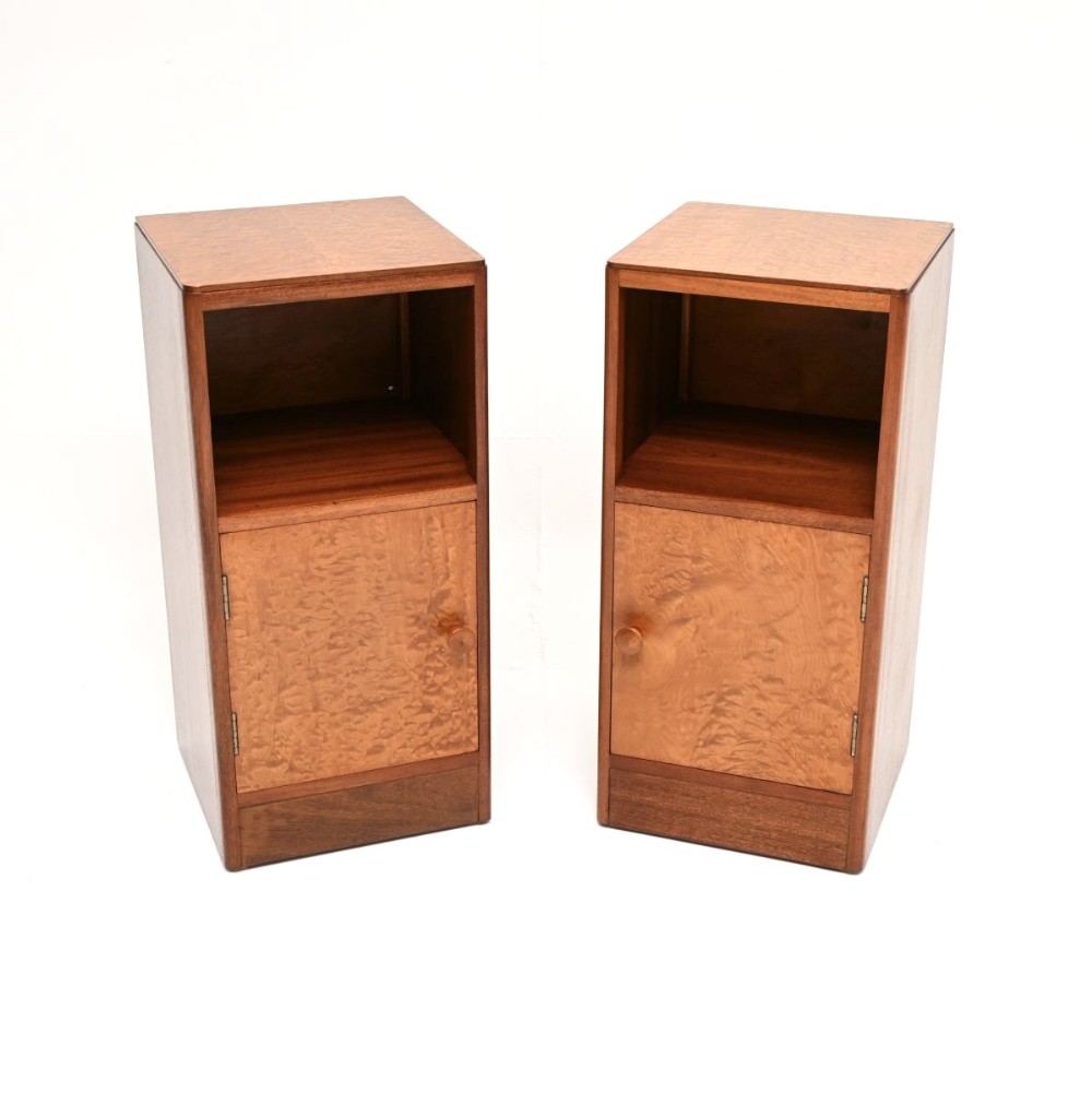 A pair of matching Art Deco bedside cabinets crafted from mahogany with birds eye maple veneered door panels and open upper shelves.