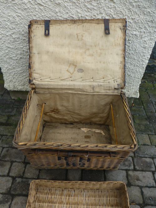 fig 2. A large 19th-century woven brown wicker travelling trunk with iron latches and stencilled black lettering on the front.