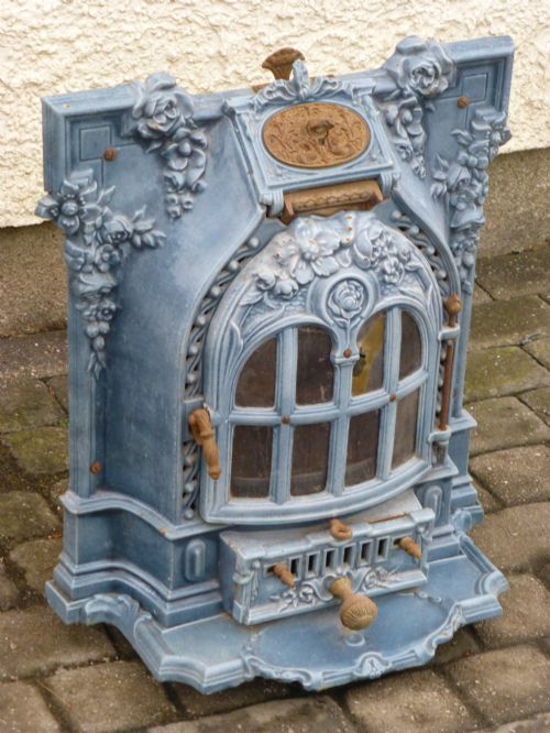 fig 1. A French Art Nouveau slate blue enamelled cast iron log burner stove adorned with floral relief mouldings and an arched windowed door.