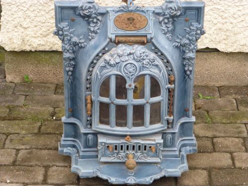 fig 2. A French Art Nouveau slate blue enamelled cast iron log burner stove adorned with floral relief mouldings and an arched windowed door.