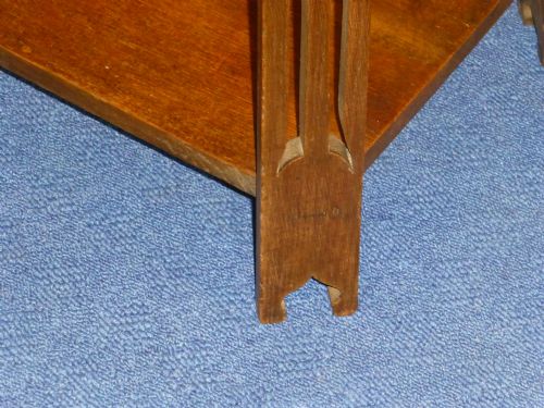 fig 2. An Arts and Crafts solid oak occasional table featuring a square top with fine chequered inlay, a lower shelf, and vertical leg supports with heart-shaped cutouts.