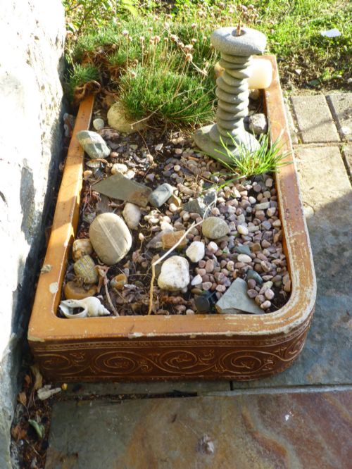 fig 1. A low rectangular salt-glazed stoneware planter trough featuring rounded corners and carved scrollwork relief around the sides.