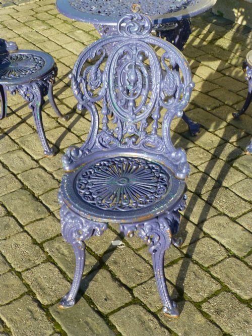 fig 1. A nineteenth-century painted purple cast iron garden suite consisting of a round openwork table and four matching ornate medallion chairs.