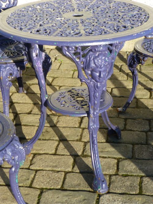 fig 3. A nineteenth-century painted purple cast iron garden suite consisting of a round openwork table and four matching ornate medallion chairs.