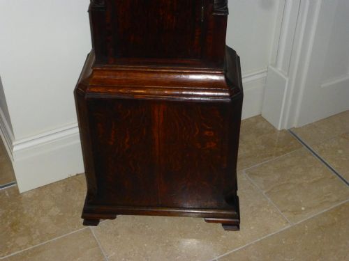 fig 2. An eighteenth-century dark oak and walnut longcase clock featuring a square brass dial, turned columns, and a hood with a moulded cornice.
