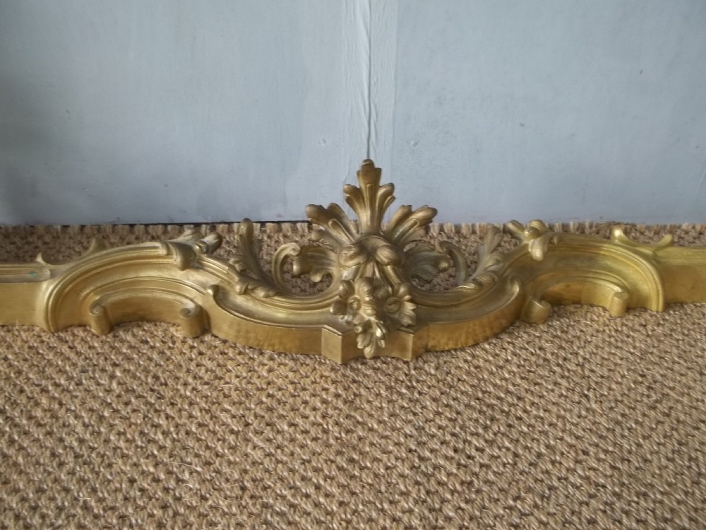 A 19th-century gilt bronze Rococo fireplace fender featuring adjustable scrolling acanthus leaf chenets at each end. View VI